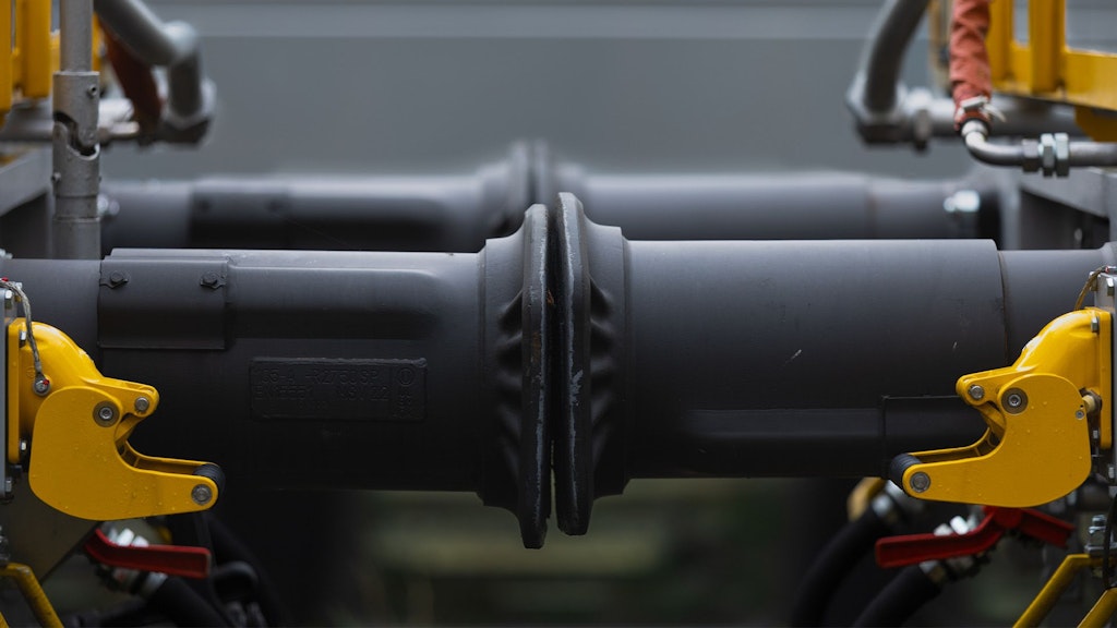 Un mécanicien monte un attelage automatique sur un wagon en atelier.