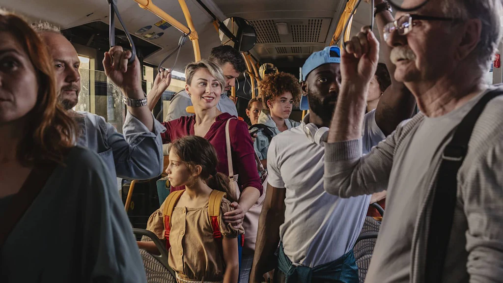 Ein Bus mit vielen stehenden weiblichen und männlichen Fahrgästen verschiedener Generationen