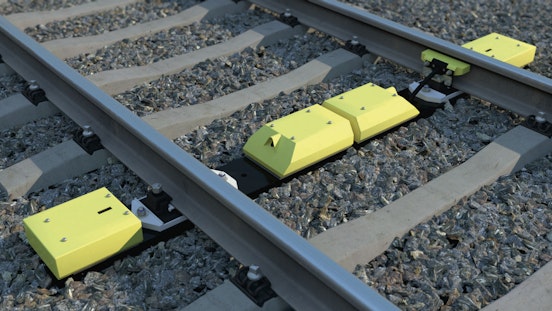 Gelbe Kästchen, die zwischen den Gleisen montiert sind.