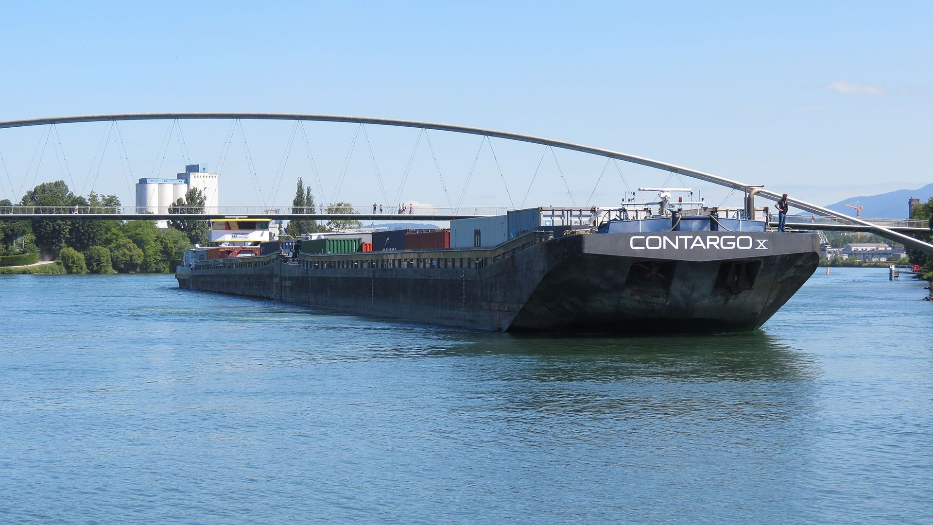 Ein mit Containern beladenes Schiff liegt vor einer Brücke im Rhein.