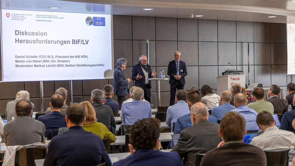 Ein Moderator und zwei Teilnehmer sprechen an einer Podiumsdiskussion. 