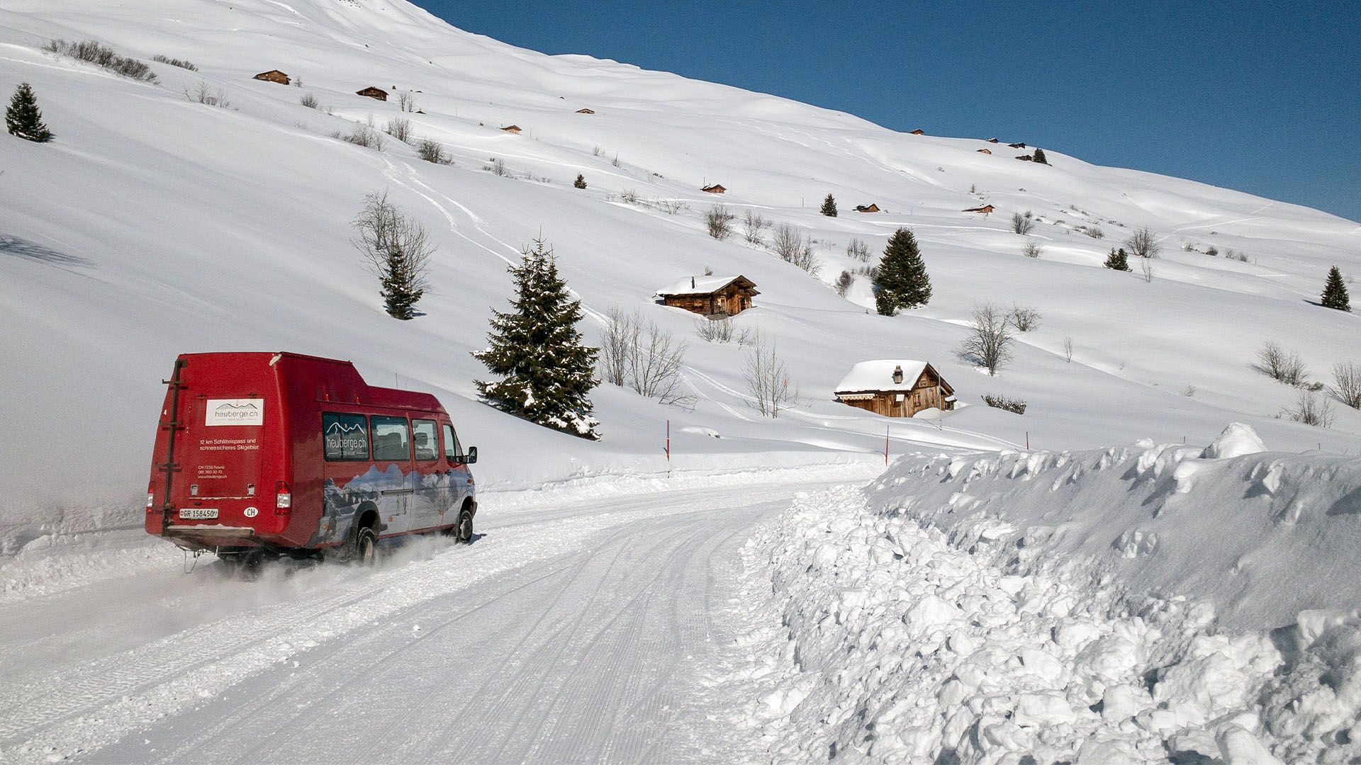 Ein Kleinbus fährt auf schneebedeckter Strasse talwärts