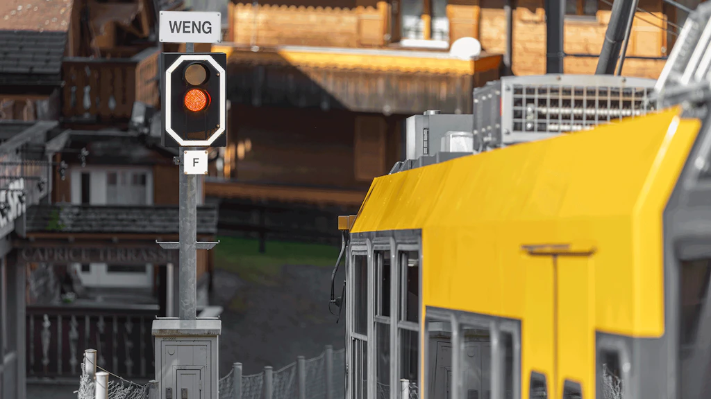 Un train de la Wengernalpbahn attend devant un signal principal rouge.
