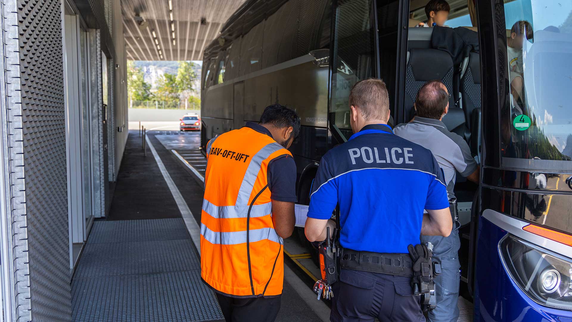 Un collaborateur de l’OFT et un policier cantonal contrôlent un car de tourisme.