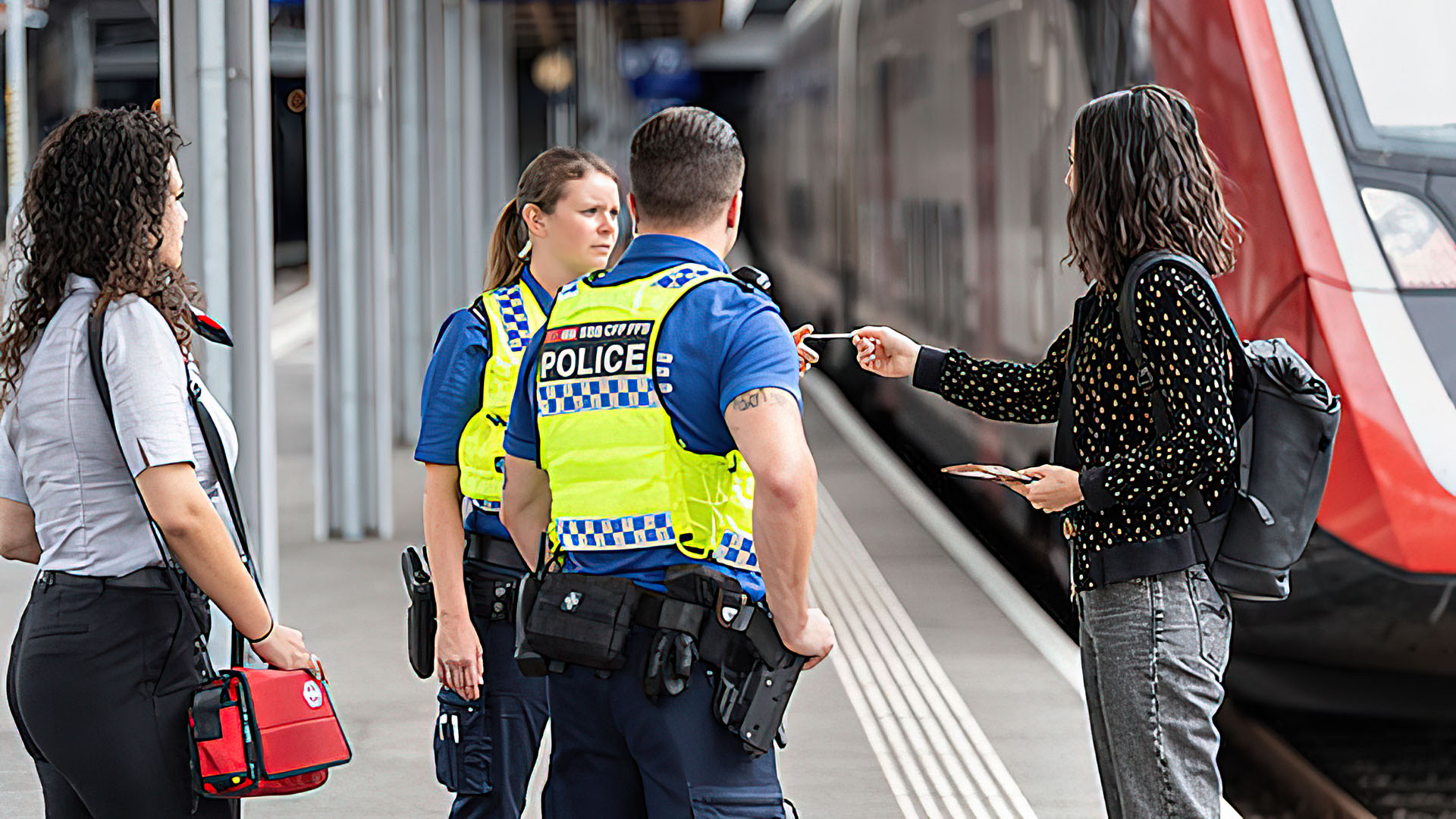 Une usagère en discussion avec deux collaborateurs en uniforme de la police des transports.