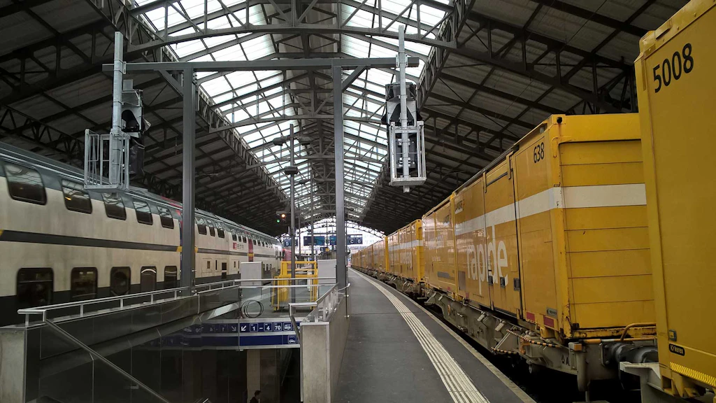 Quai de la gare de Lausanne. À droite, un train de marchandises de la Poste, à gauche, un train de voyageurs des CFF.