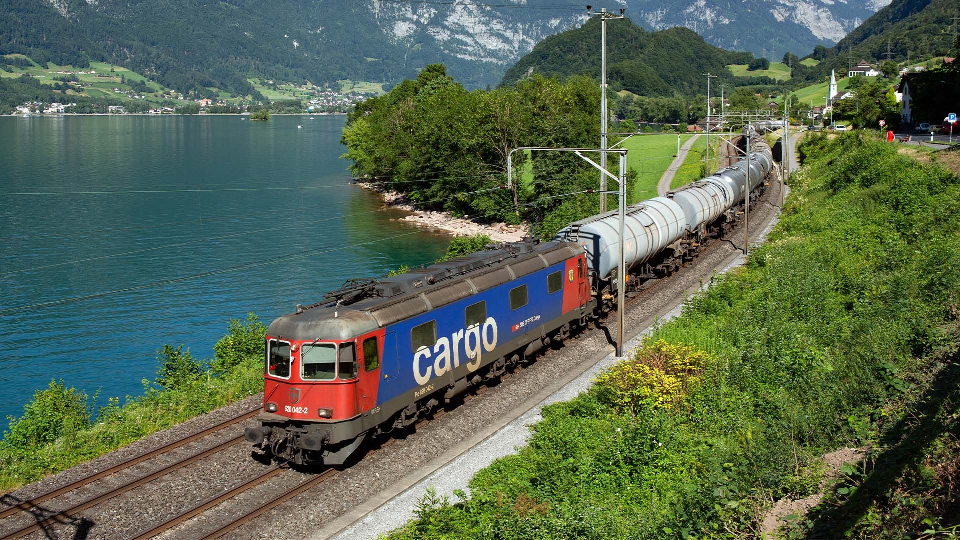 Un train de marchandises de CFF Cargo longe les rives d’un lac.
