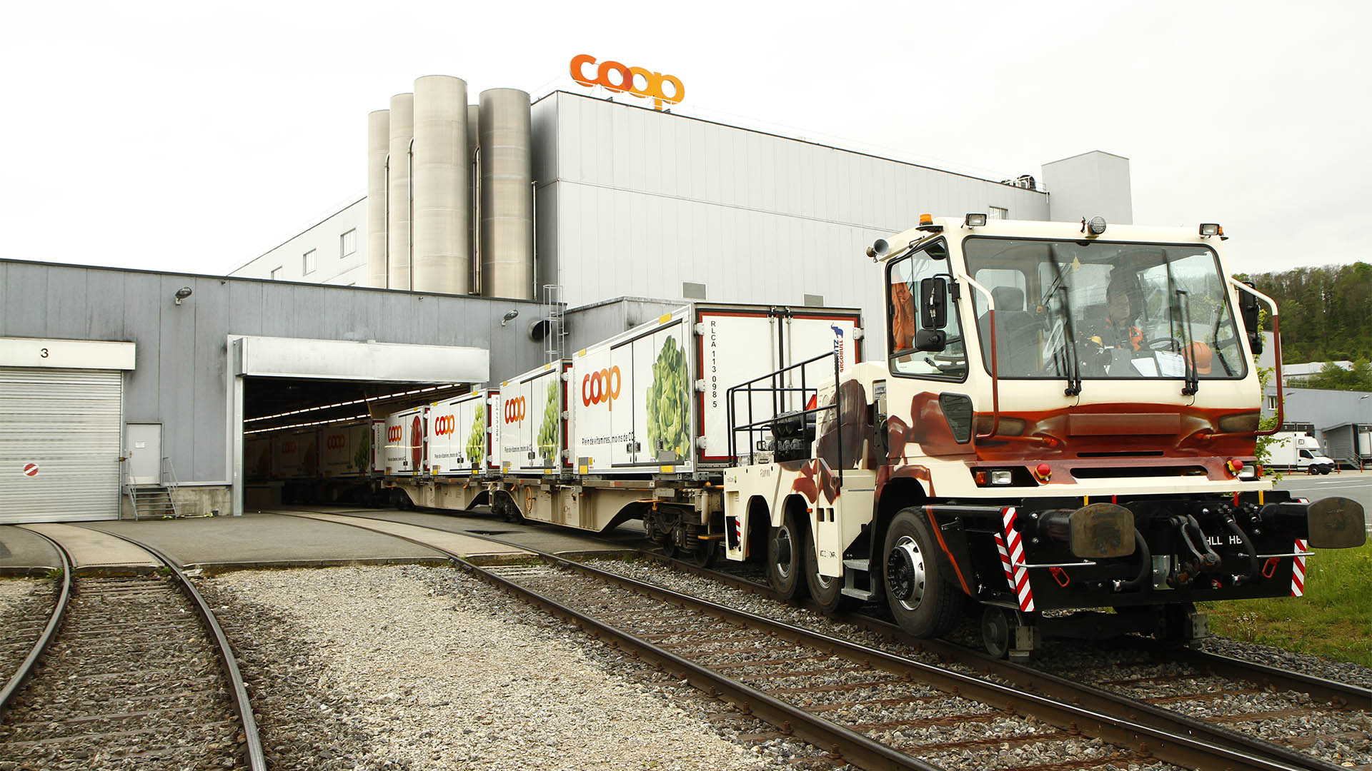 Sur une voie de raccordement, des wagons quittent un site de production Coop.