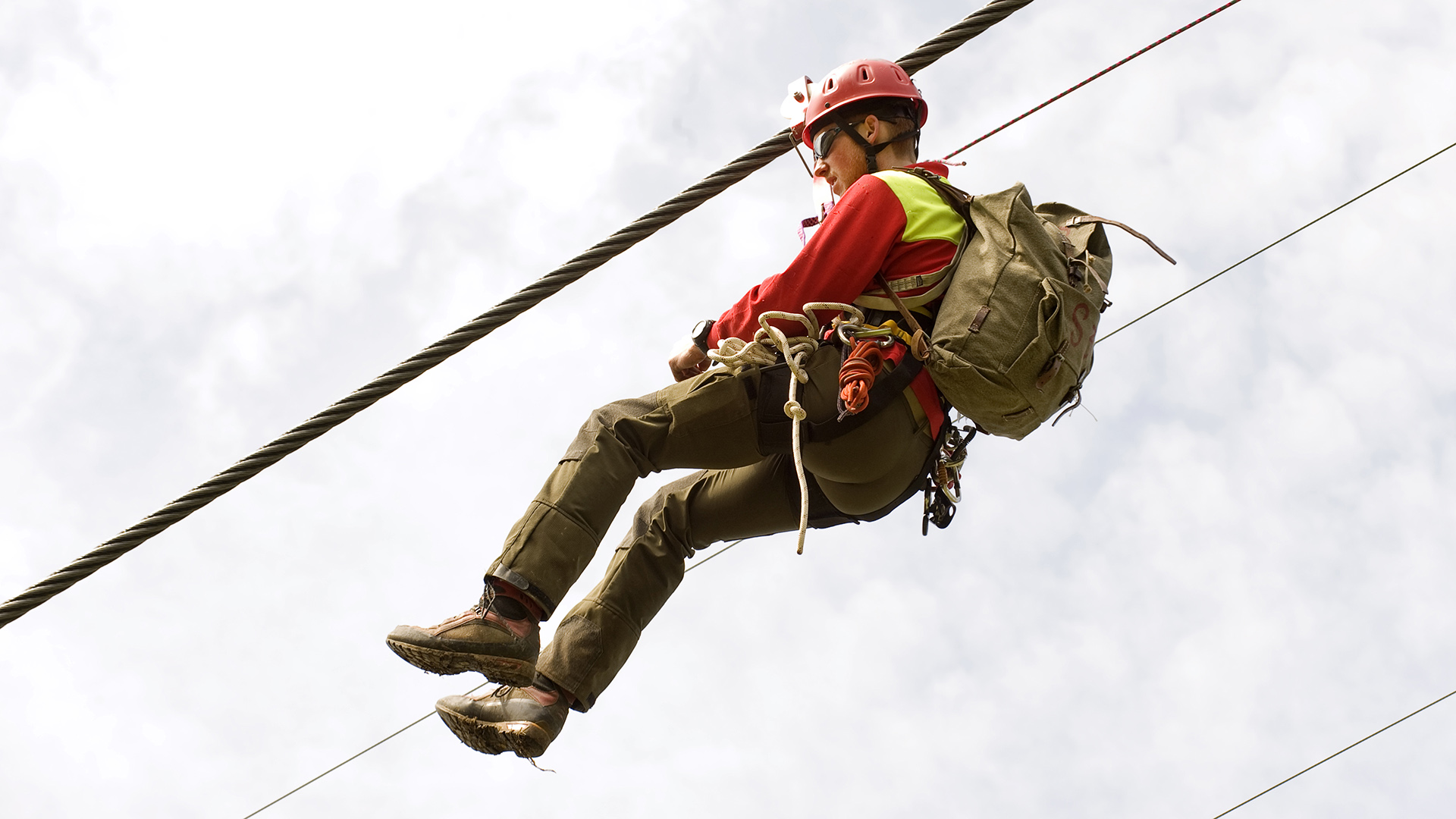 Un ispettore sospeso nell’aria, agganciato alla corda di una funivia.