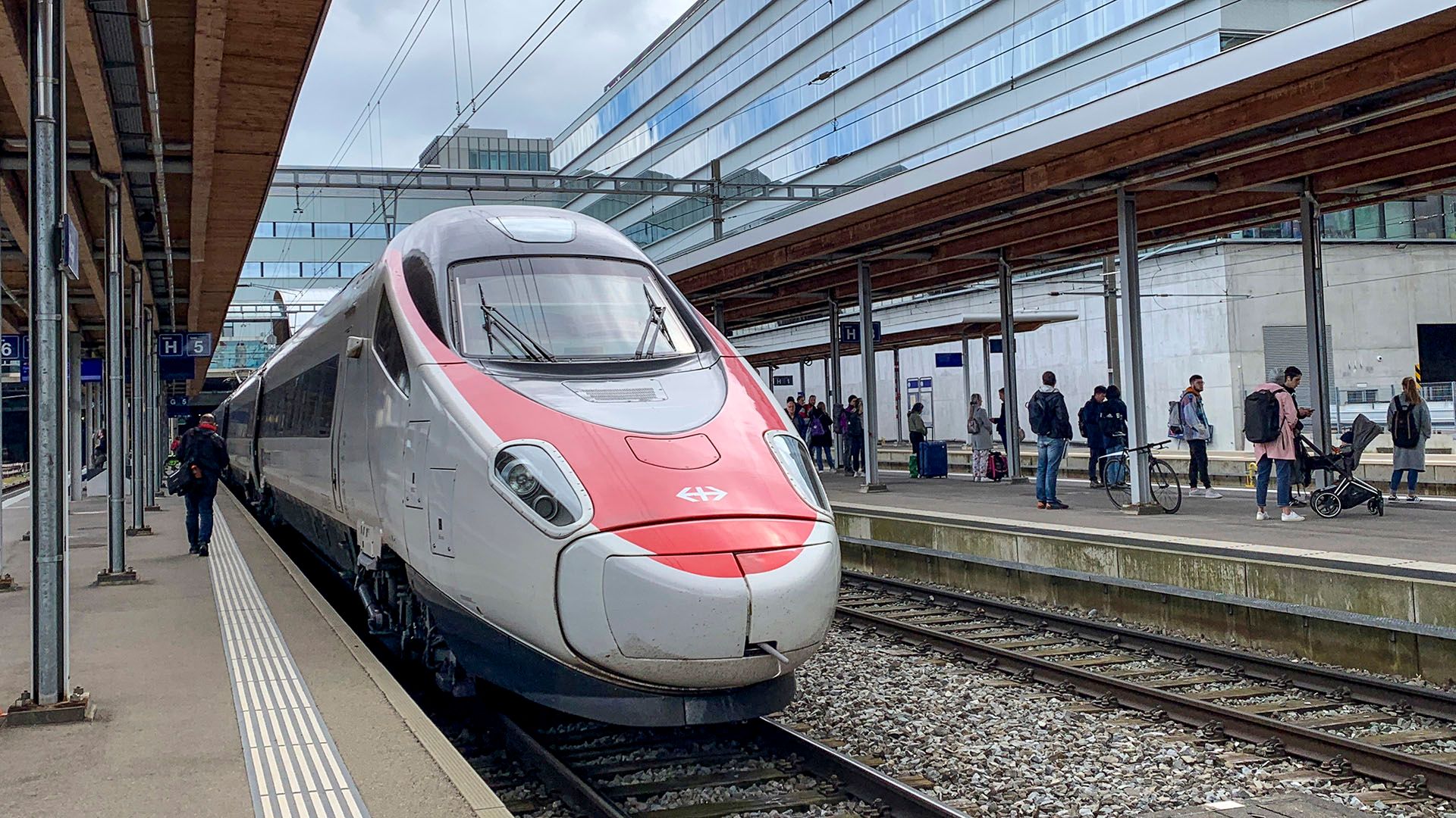 Un treno a lunga percorrenza e passeggeri in attesa alla stazione di Berna.