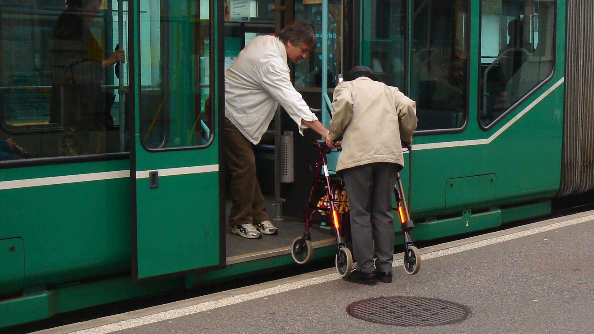 Un uomo con un deambulatore sale su un tram