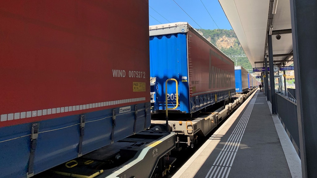 Un treno merci con container rossi alla stazione di Mendrisio